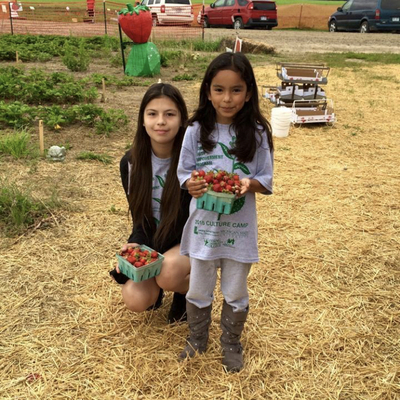 an older and younger student posing with strawberries in boxes