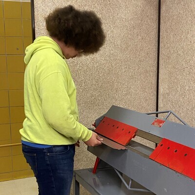 Student using red and grey machinery