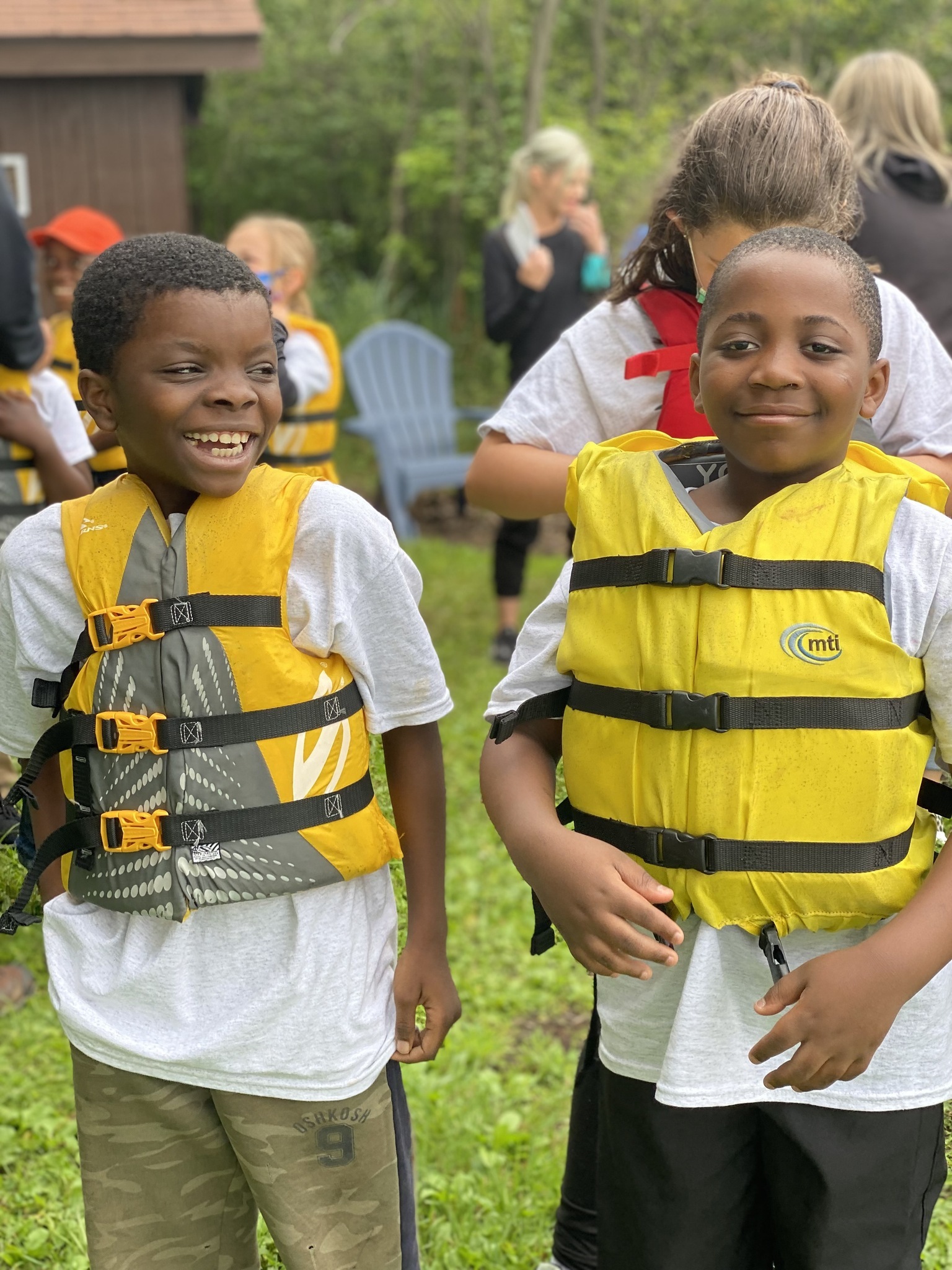 Two students smile while wearing yellow life jackets
