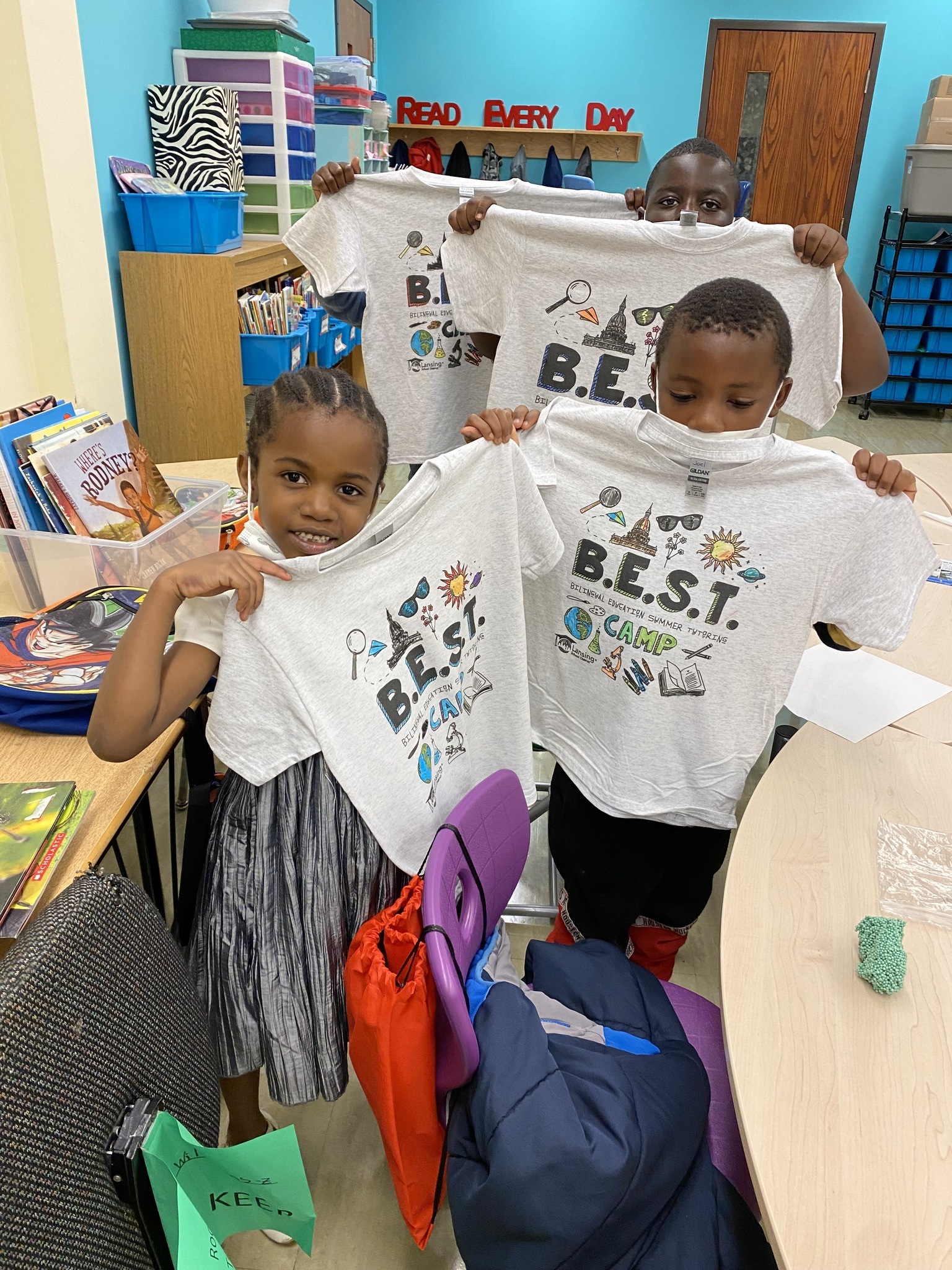 Four young students hold up their BEST Camp shirts