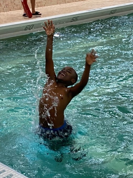 A student jumping out of the water in a swimming pool